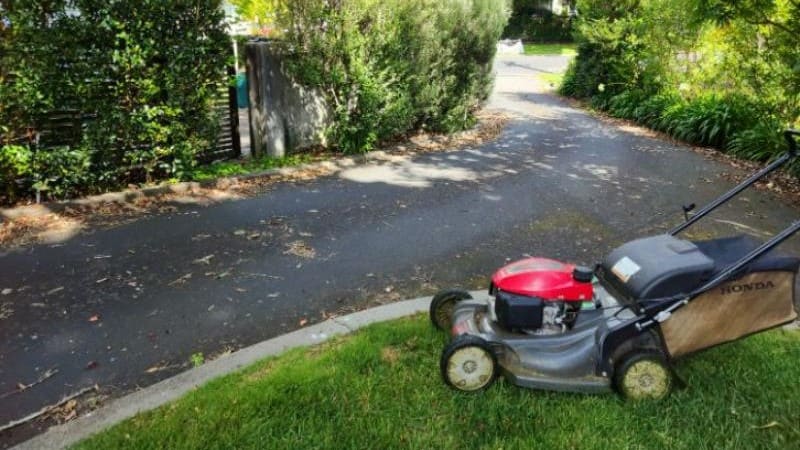 Honda mower on a lawn edge beside a customer's driveway