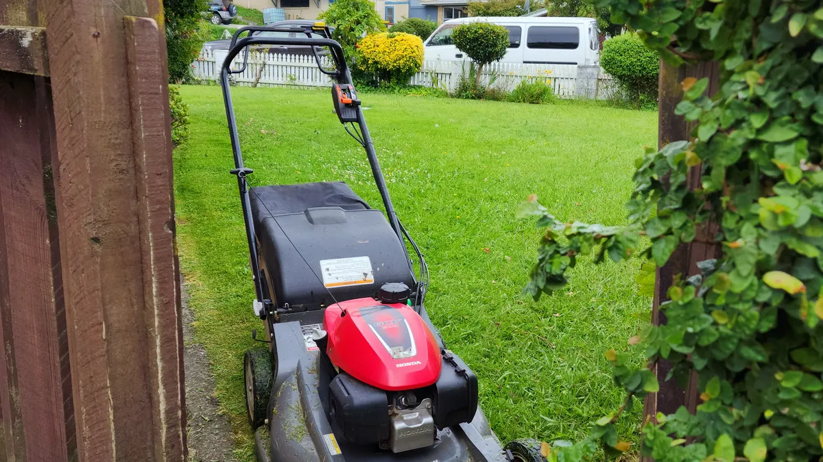 Honda mower beside a side fence