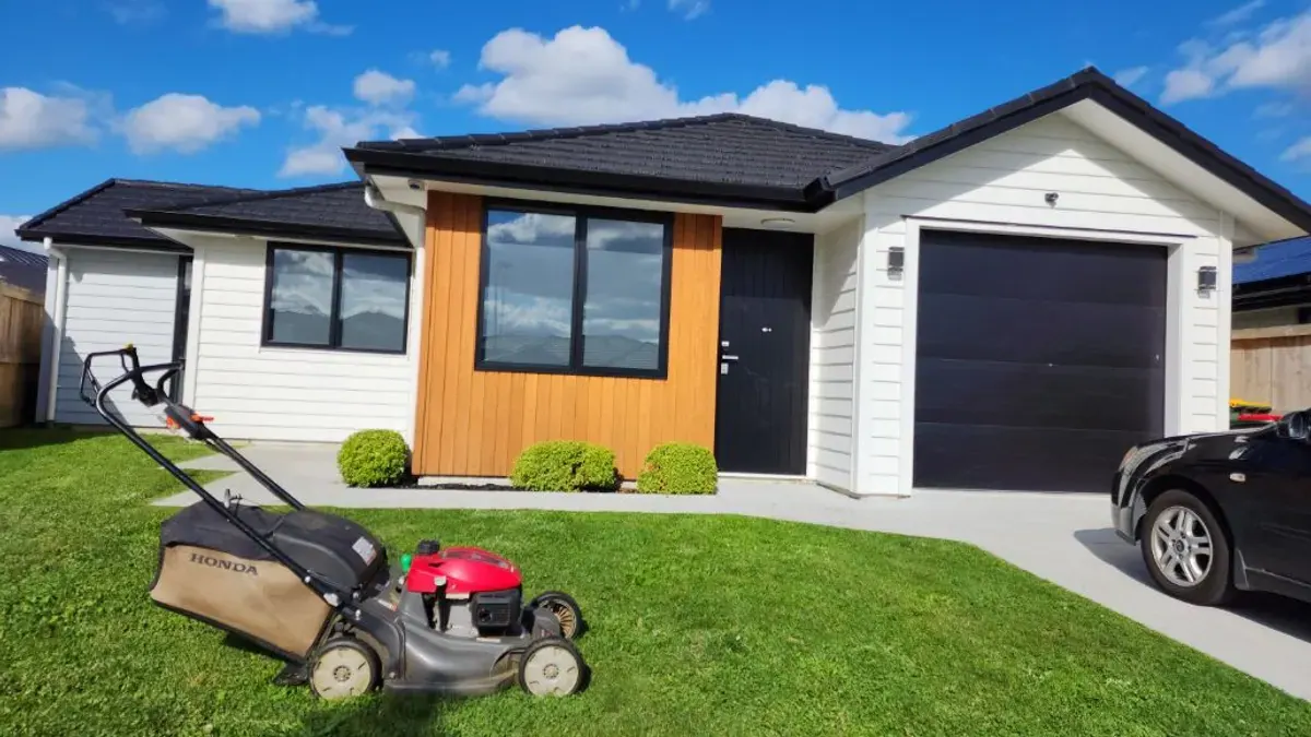 Mower on a tidy front lawn outside a new house