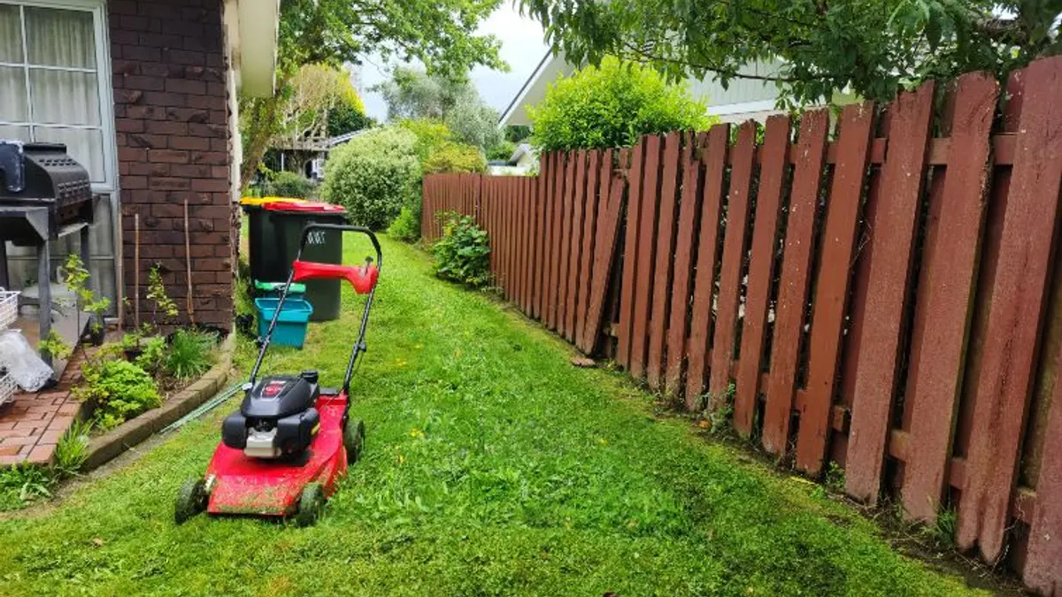 Mower along a wooden fence line