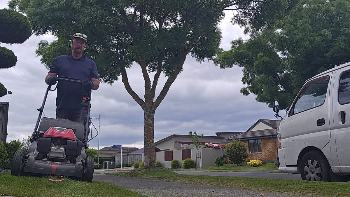 Stuart mowing a berm with a Honda mower, van parked on the street