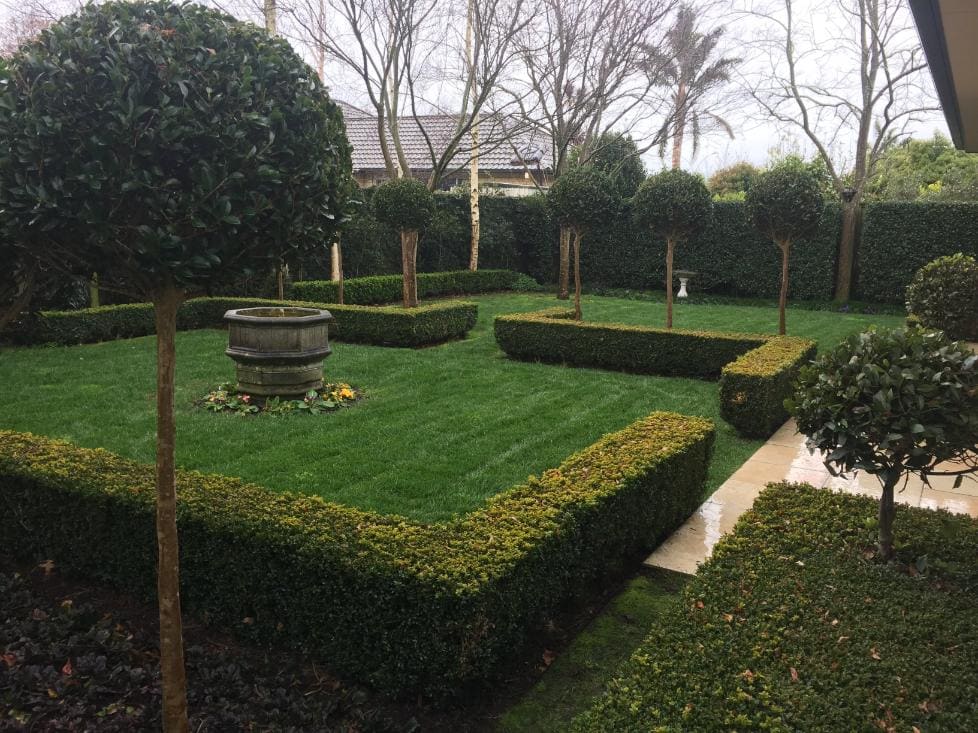 Formal garden with clipped box hedges, topiary trees and a striped lawn