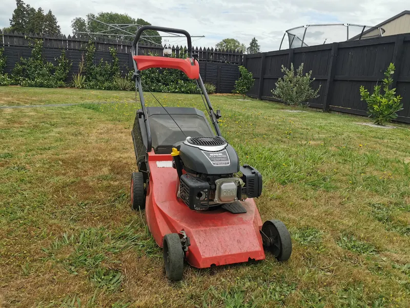 Red push mower on a freshly cut lawn