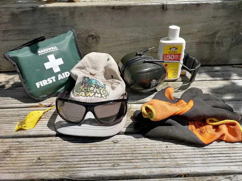 First aid kit, cap, safety glasses, earmuffs, gloves and sunscreen on a deck