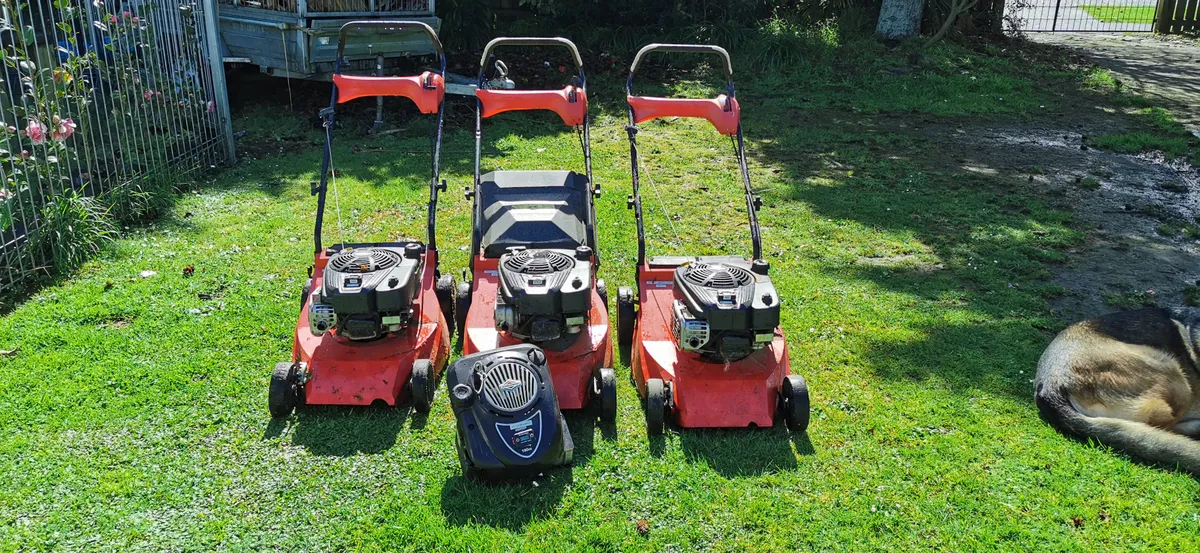 Three push mowers lined up on a lawn ready for the day