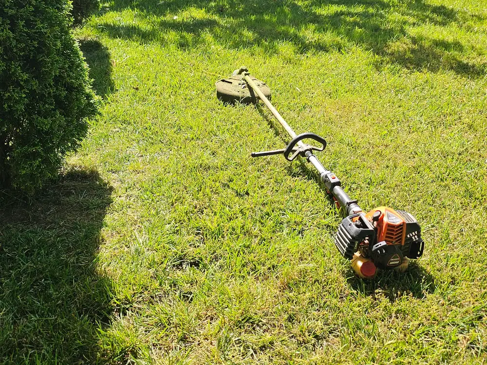 Line trimmer lying on a sunny lawn